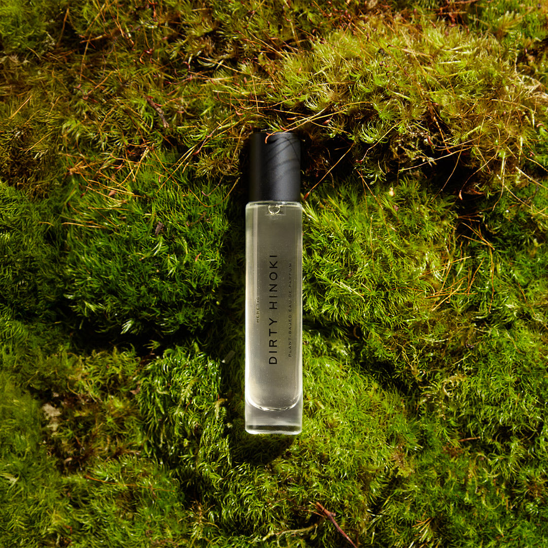 Clear bottle with black cap on a mossy surface, featuring 'DIRTY PINOKI' branding.