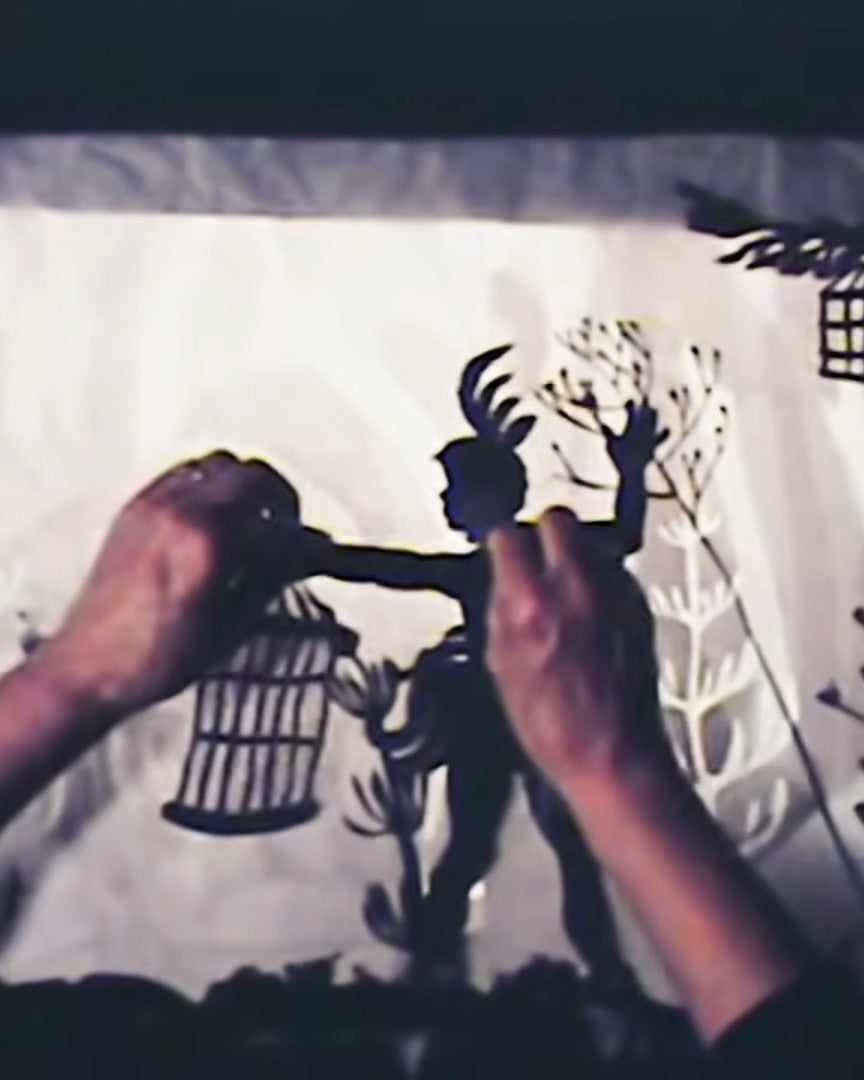 Shadow puppetry with hands holding black cut-out figures against a light background