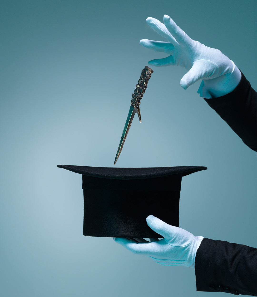 A black top hat held up by gloved hands with a silver dagger floating above it, set against a solid teal-blue background.