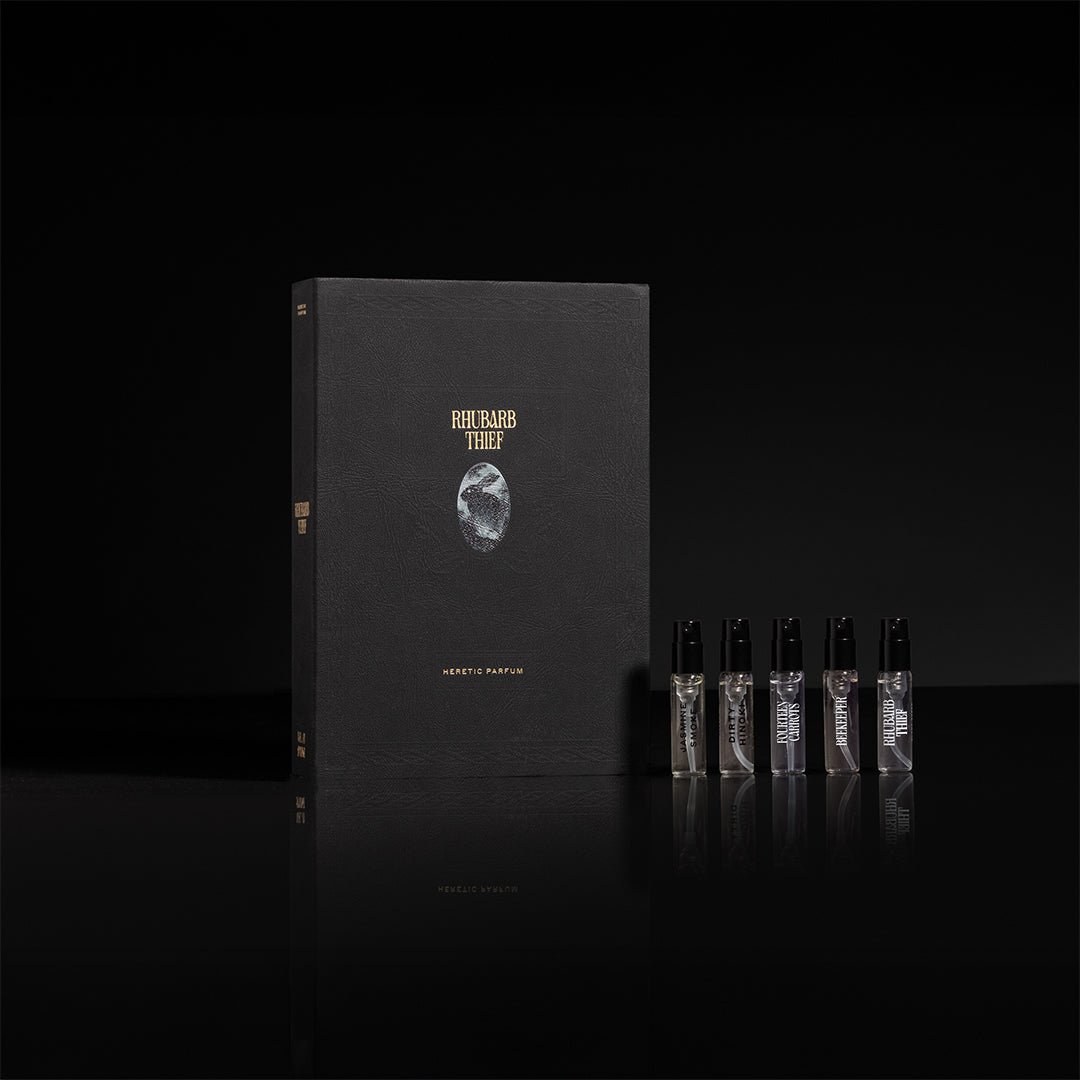 Black book with gold text and five small bottles on a black background
